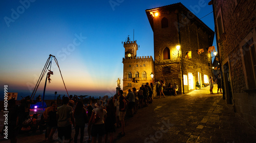 Public Palace in San Marino at sunset. Crowd looking at street artist.