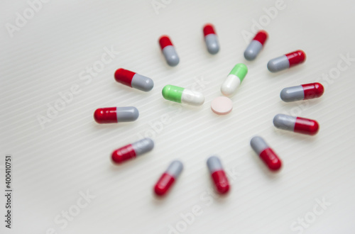 Pills arrange in the shape of clock's on white background. Selective focus on green and white capsule. Healthcare and medical concept.