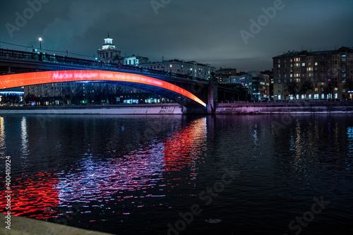 evening winter cityscape with river bridge and illuminated buildings © константин константи