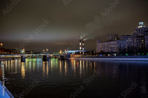 evening winter cityscape with river bridge and illuminated buildings