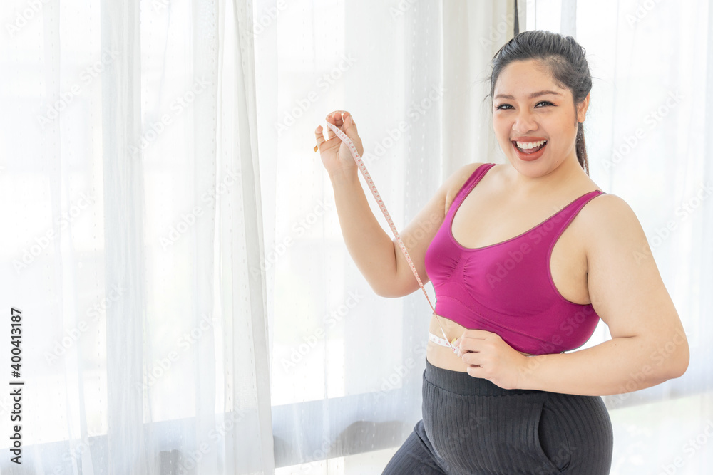 asian fat women , Fat girl , Chubby, overweight measuring her waist in the bedroom - Woman diet lifestyle overweight problem concept asian fat women , Fat girl , Chubby, overweight measuring her waist in the bedroom - Woman diet lifestyle overweight problem concept