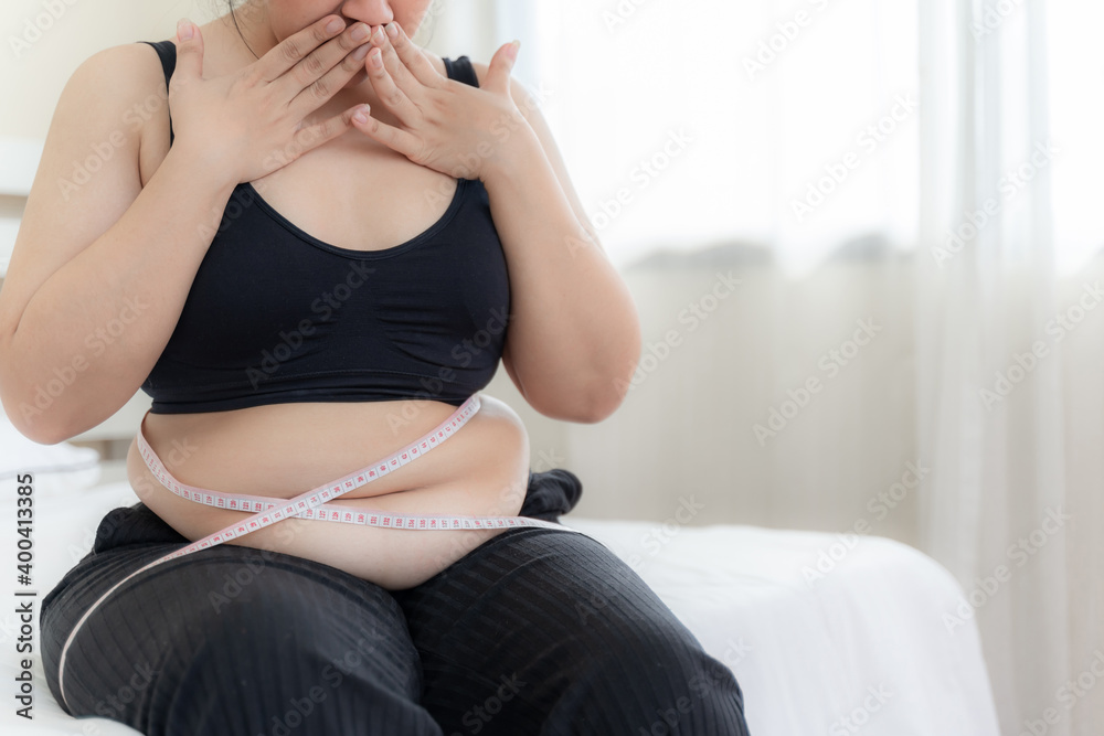 asian fat women , Fat girl , Chubby, overweight measuring her waist in the  bedroom - Woman diet lifestyle overweight problem concept Stock Photo