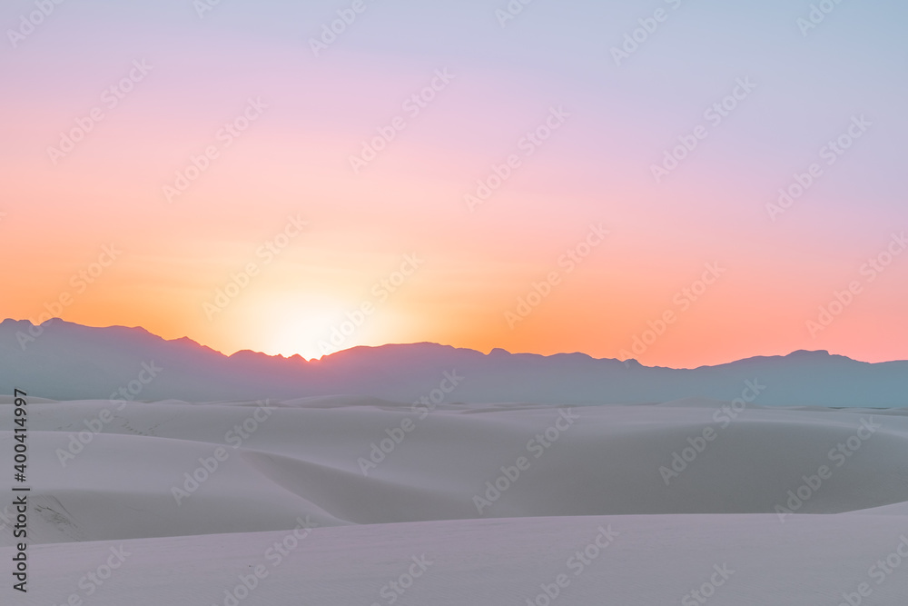 A vibrant, colorful sunset over the white gypsum sand dune layers of  White Sands National Park, New Mexico, USA.
