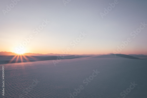 Sunburst above the gypsum sand dunes during a beautiful, vibrant sunset in White Sands National Park, New Mexico, USA.