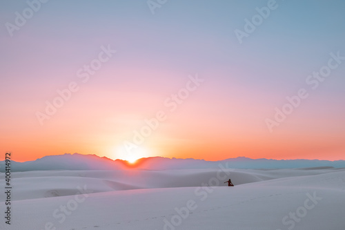 Silhouette of a female/girl/woman watching the colorful sunset over the sand dunes of White Sands National Park in New Mexico, USA.