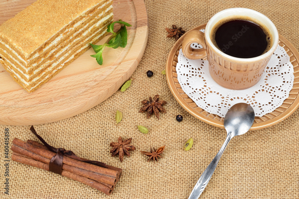 A piece of honey cake on a wooden cutting board, next to a cup of black coffee on a saucer. A piece of honey cake on a wooden cutting board, next to a cup of black coffee on a saucer.
