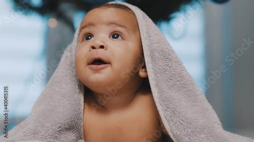 Принти на полотні Adorable dark skin baby covered with towel having fun tummy time