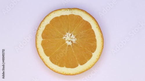 Fresh, ripe yellow orange slice spinning on a white backgroung. Citrus fruit rotating  continously  photo