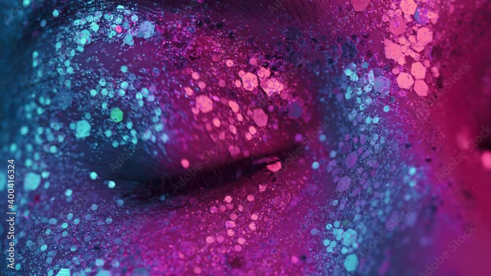 Female eye blinking under neon light 4K. Girl with beautiful glittering makeup, close up. Nightlife, night club concept.