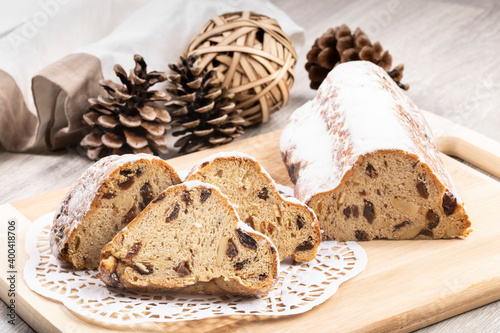 A traditional German Stolle (Christmas loaf) with nuts and raisins cut into slices on a black plate with a doillie photo