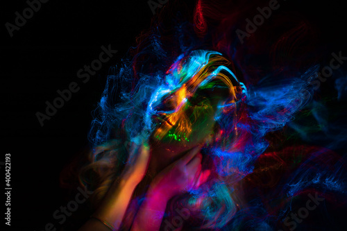 Portrait of a beautiful woman in colored beams of a projector. Streaks of light and shadow on the skin.