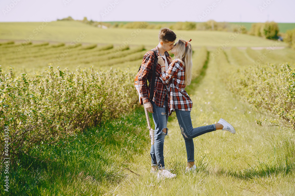 Man and woman in a field on spring day. Couple in love spend time in spring field. Grass on background. Man with electro guitar. Man and woman in a field on spring day. Couple in love spend time in spring field. Grass on background. Man with electro guitar.