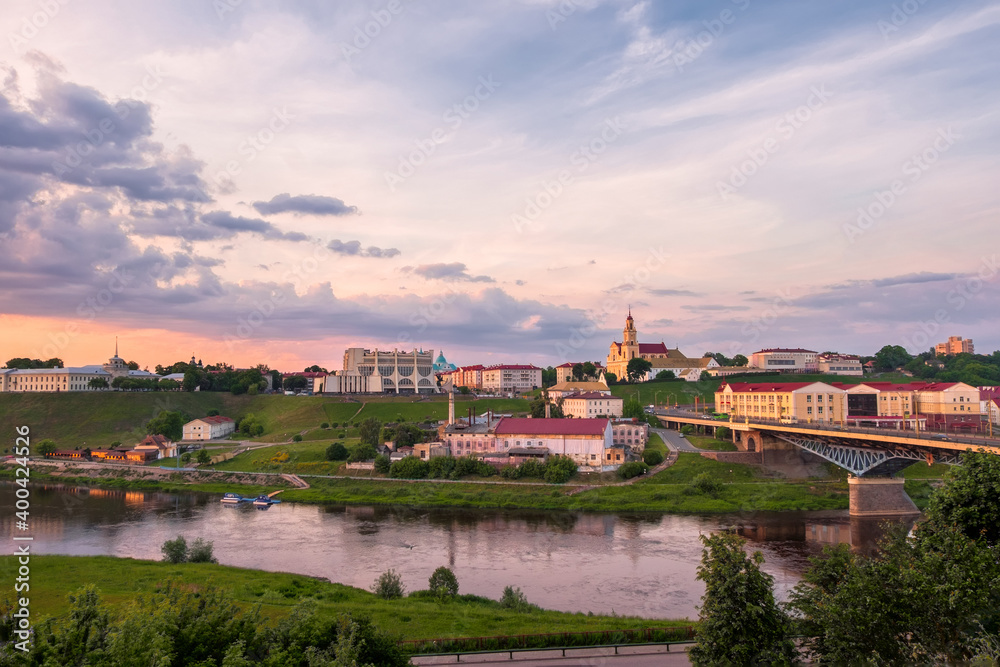 Belarus.Sights and views of the city of Grodno. On the riverbank Neman there are the buildings of the theater and the church at illuminated by the rays of the setting sun.