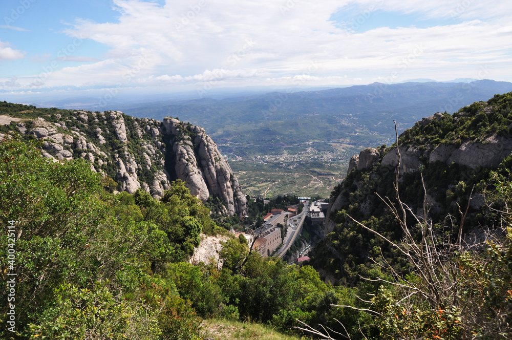 Fototapeta premium View from the mountain to the buildings and the valley. Mountain landscape with green vegetation.