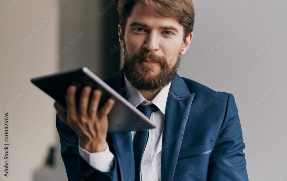 A business man in a suit with a tablet in the hands of a technology manager A business man in a suit with a tablet in the hands of a technology manager
