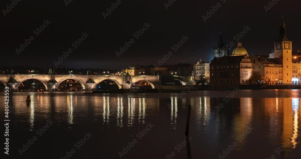 time lapse view of Charles Bridge and flowing Vltava river at night in the center of Prague in the Czech Republic
