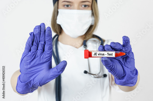 The doctor holds in his hands a test tube with blood tests for the virus -JE, with the other hand he makes a gesture - stop. photo