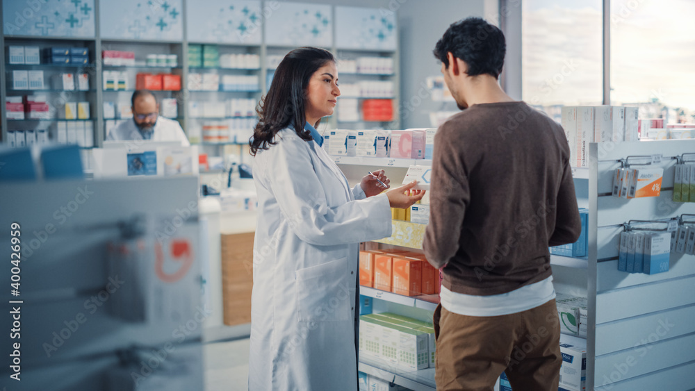Obraz premium Pharmacy Drugstore: Hispanic Man Chooses to Buy Medicine, Drugs, Vitamins, Professional Female Pharmacist Helping Customer with Recommendation. Modern Pharma Store Shelves with Health Care Products