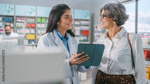 Pharmacy Drugstore: Senior Woman Chooses to Buy Medicins. Professional, Helpful Pharmacist Uses Digital Tablet Computer and Advicing Customer Best Option. Modern Pharma Store Health Care Products photo
