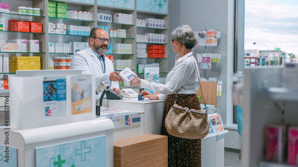 Obraz premium Pharmacy Drugstore Checkout Cashier Counter: Portrait of Friendly Pharmacist Recommending Medicine to Senior Woman which She buysWith use of Credit Card. Store with Health Care Products