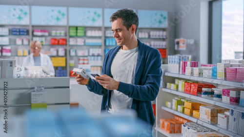 Pharmacy Drugstore: Portrait of Handsome Young Man Browsing Shelves to Buy Medicine, Drugs, Vitamins, Supplements, Found Right One. Pharma Store, Shelves full of Health Care, Welness Products