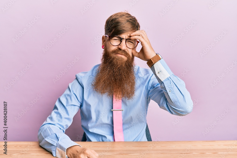 Young irish redhead man wearing business shirt and tie sitting on the table worried and stressed about a problem with hand on forehead, nervous and anxious for crisis Young irish redhead man wearing business shirt and tie sitting on the table worried and stressed about a problem with hand on forehead, nervous and anxious for crisis