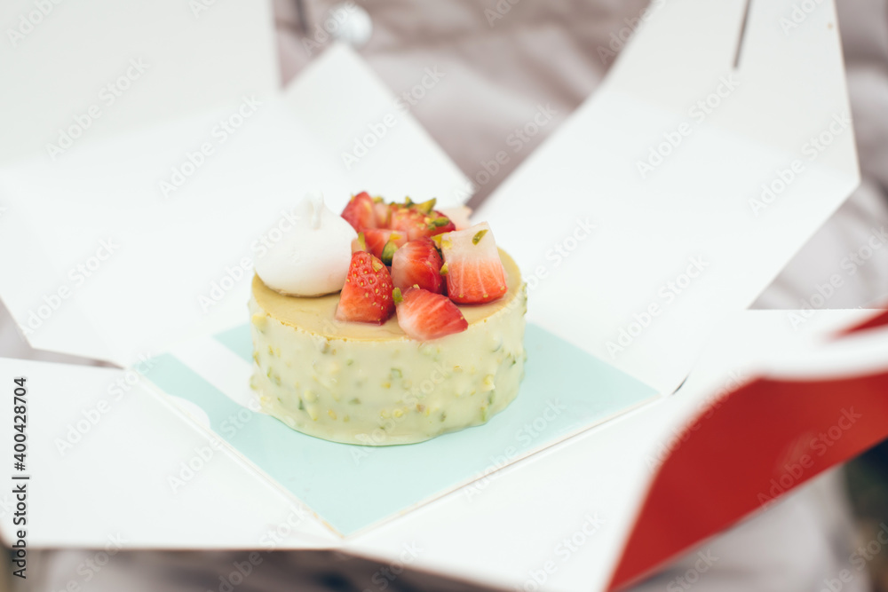 Close-up of pistachio pastry flavored with fresh strawberries gluten free and vegan in take away box. Natural light, selective focus photo