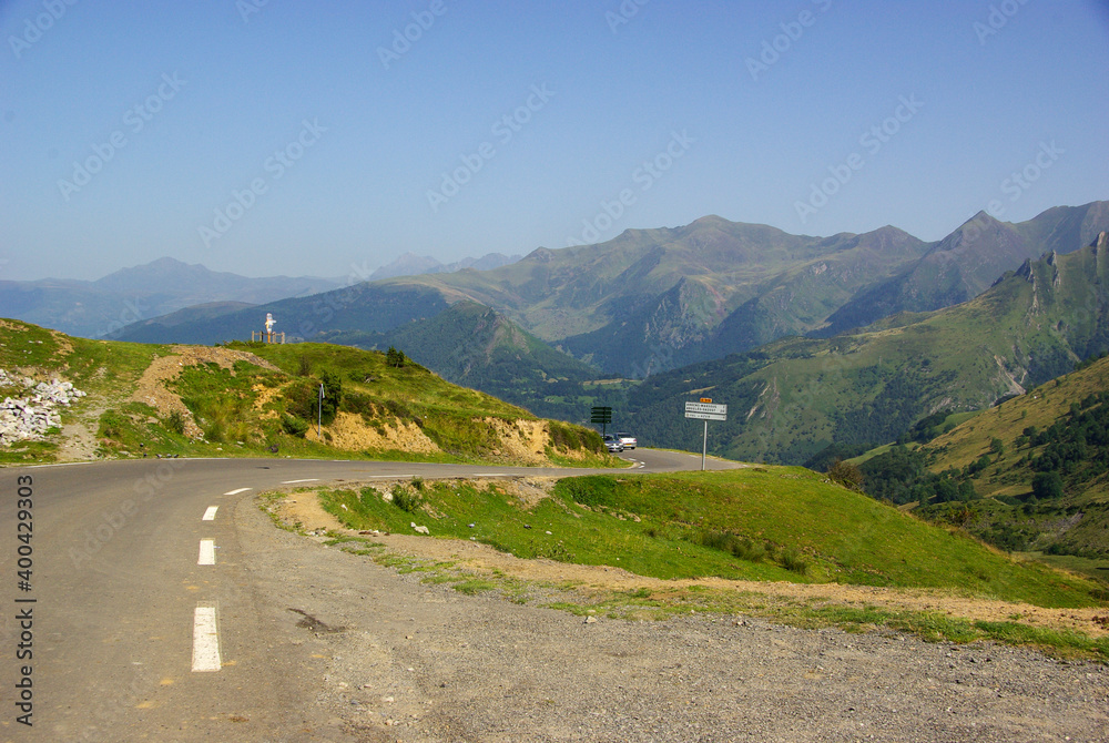  Mountain road surrounded by green meadows through the French Pyrenees. High quality photo. Copy Space for characters or letters