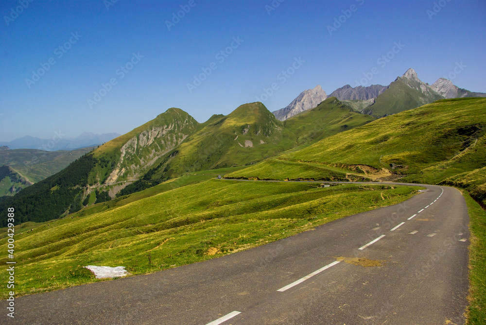 Mountain road surrounded by green meadows through the French Pyrenees. High quality photo. Copy Space for characters or letters