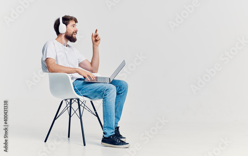 Man sitting on chair in front of laptop in headphones communication technology isolated background