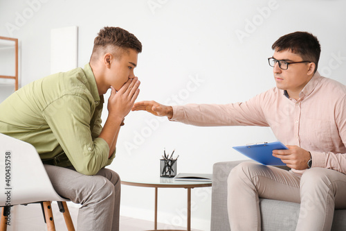 Psychologist working with teenage boy in office