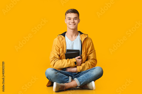 Teenage boy with books on color background © Pixel-Shot
