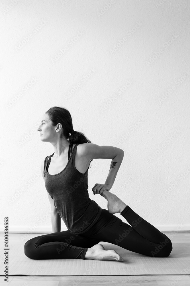 A dark-haired European woman in her 30’s practices yoga at home. Meditation, stretching and mindfulness to achieve physical and spiritual health. Vertical format.
