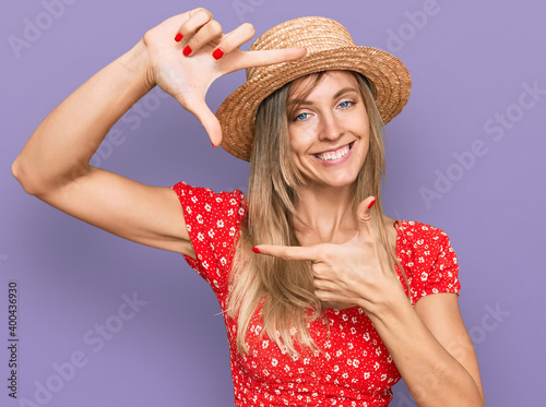 Beautiful caucasian woman wearing summer hat smiling making frame with hands and fingers with happy face. creativity and photography concept.