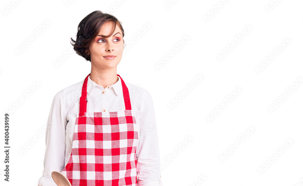Beautiful young woman with short hair wearing professional cook apron smiling looking to the side and staring away thinking. Beautiful young woman with short hair wearing professional cook apron smiling looking to the side and staring away thinking.