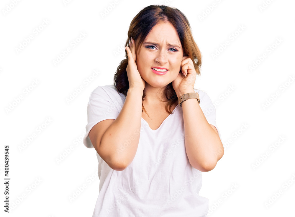 Young beautiful caucasian woman wearing casual white tshirt covering ears with fingers with annoyed expression for the noise of loud music. deaf concept. Young beautiful caucasian woman wearing casual white tshirt covering ears with fingers with annoyed expression for the noise of loud music. deaf concept.