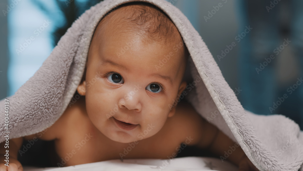 Adorable dark skin baby covered with towel having fun tummy time. High quality photo Adorable dark skin baby covered with towel having fun tummy time. High quality photo