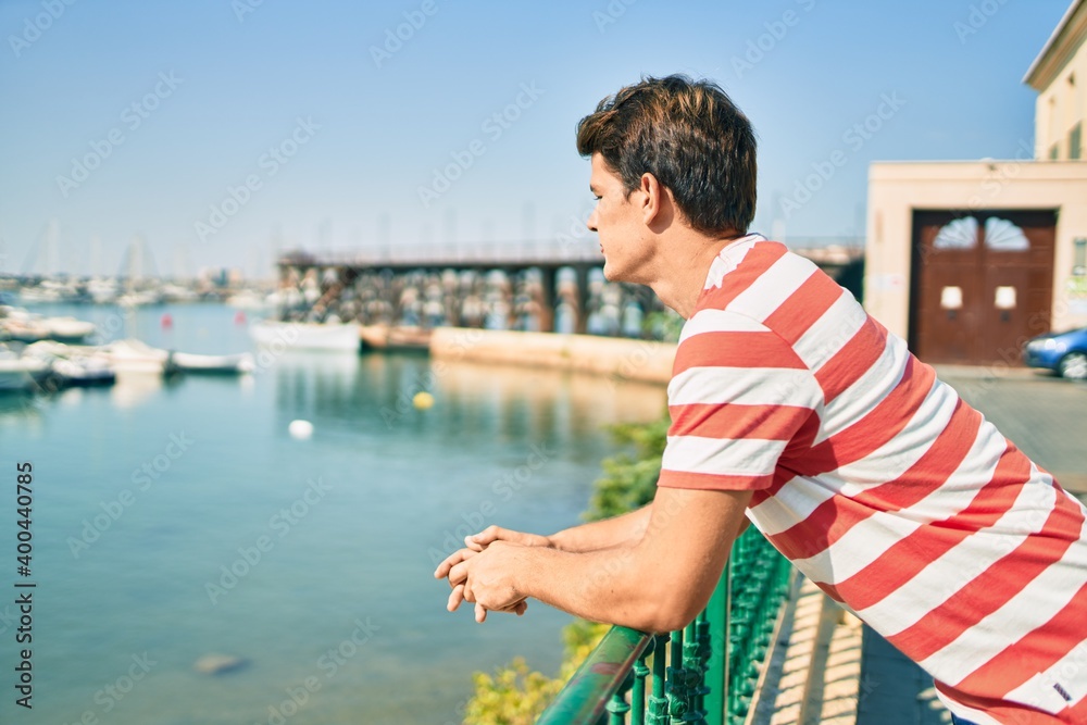 Young caucasian man smiling happy leaning on the balustrade at river