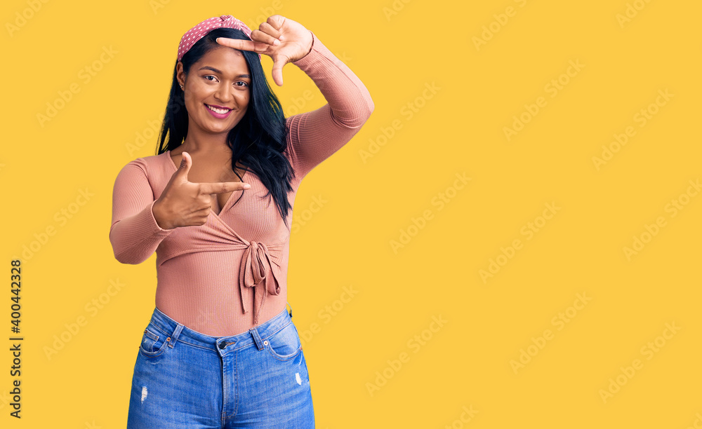 Hispanic woman with long hair wearing casual clothes smiling making frame with hands and fingers with happy face. creativity and photography concept. Hispanic woman with long hair wearing casual clothes smiling making frame with hands and fingers with happy face. creativity and photography concept.