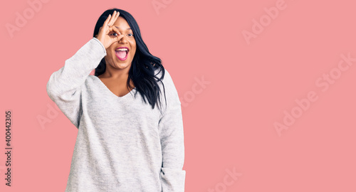Hispanic woman with long hair wearing casual clothes doing ok gesture with hand smiling, eye looking through fingers with happy face. © Krakenimages.com