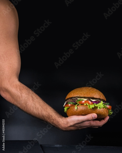 A large Burger on a dark background. The hands of the chef. Photo of a hamburger.