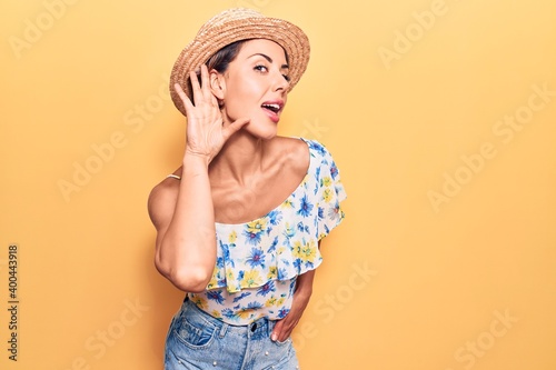 Young beautiful woman wearing summer hat smiling with hand over ear listening and hearing to rumor or gossip. deafness concept.