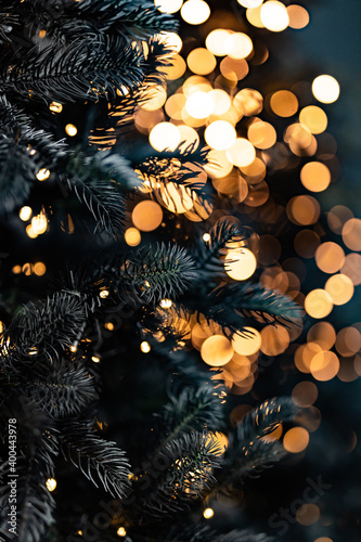 Christmas tree outdoor with snow, lights bokeh around, and snow falling, Christmas atmosphere. Light night blur bokeh on christmas tree, light bokeh background.