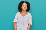 Young african american girl wearing casual clothes looking away to side with smile on face, natural expression. laughing confident.