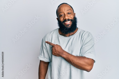 Young african american man wearing casual clothes smiling cheerful pointing with hand and finger up to the side