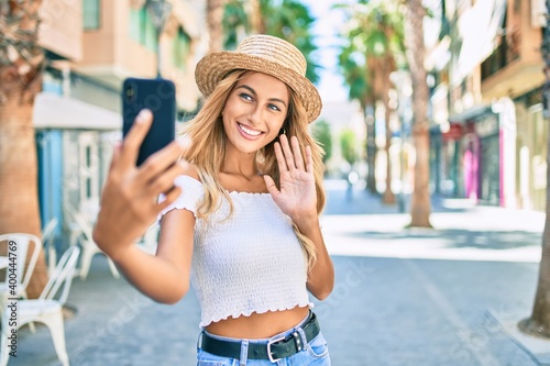 Young blonde tourist girl smiling happy doing video call using smartphone at the city. © Krakenimages.com