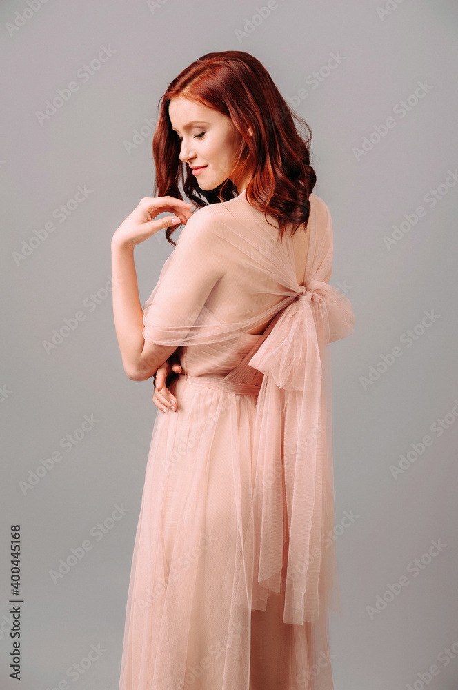 Elegant salmon dress. Beautiful peach chiffon evening gown. Studio portrait of young brunette woman. Bridesmaid dresses. Elegant salmon dress. Beautiful peach chiffon evening gown. Studio portrait of young brunette woman. Bridesmaid dresses.