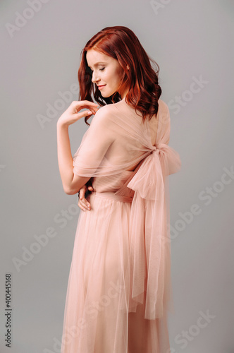 Elegant salmon dress. Beautiful peach chiffon evening gown. Studio portrait of young brunette woman. Bridesmaid dresses.