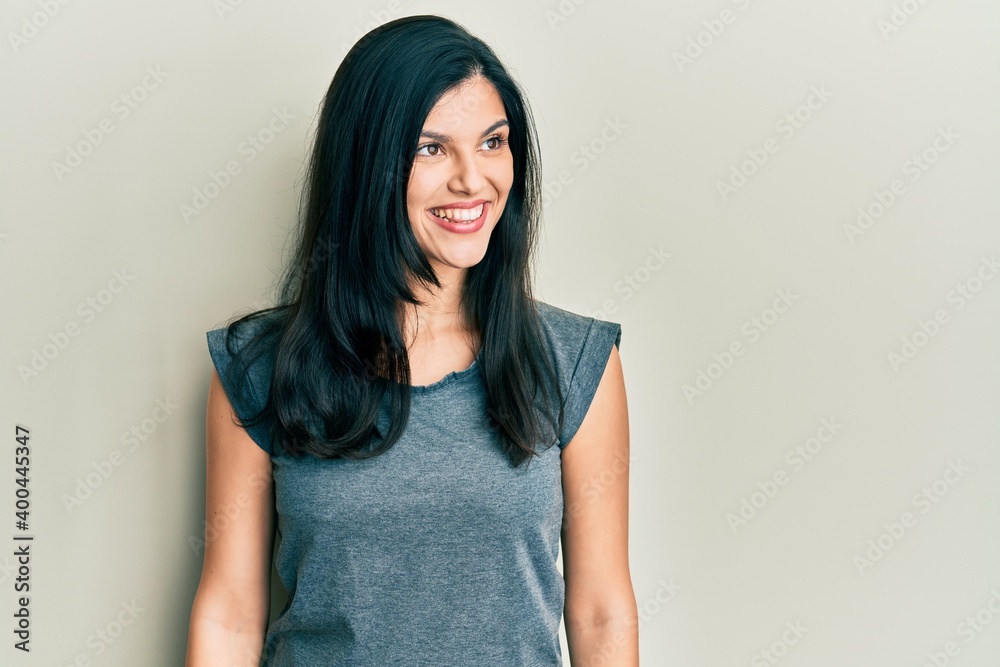 Young hispanic woman wearing casual clothes looking to side, relax profile pose with natural face and confident smile. Young hispanic woman wearing casual clothes looking to side, relax profile pose with natural face and confident smile.