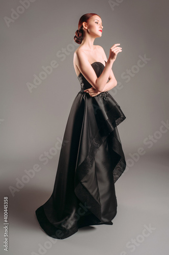 Black evening dress. Attractive young woman in studio. Posh evening gown. A line timeless dress.